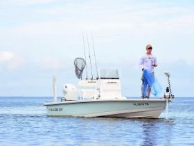 A fisherman prepares to cast a net from his Blazer Bay boat, showcasing the excitement of fishing adventures on the water.
