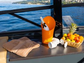 An inviting setup featuring champagne, fresh fruit, and towels on a boat, perfect for a luxurious day on the water.
