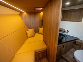 A cozy cabin interior featuring comfortable yellow seating and modern amenities, perfect for relaxation on a boat.