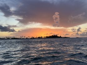 A stunning sunset over an island silhouette, showcasing vibrant colors and tranquil waters — a perfect backdrop for evening boat trips.