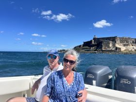 A couple enjoys a scenic boat ride with a historic fortress in the background, capturing the essence of adventure on the water.