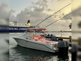 A sleek speedboat docked at the harbor, showcasing its elegant design against a backdrop of a large ferry. Ideal for fishing trips or leisurely cruises.