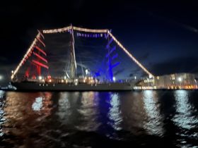 A blurry night shot of a boat illuminated with colorful lights, creating a festive atmosphere on the water.