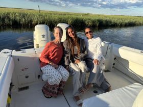 Three friends enjoy a relaxing moment on a boat, surrounded by scenic waterways and lush greenery — perfect for a day out on the water.