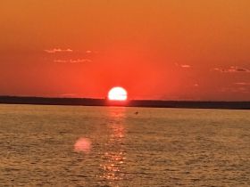 A breathtaking sunset over calm waters, creating a serene backdrop perfect for evening boat cruises.
