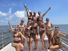 A lively group of friends celebrates on a boat, enjoying drinks and sunshine — perfect for a fun day on the water.