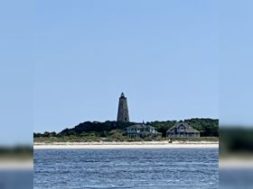 A scenic view of a lighthouse standing tall against the backdrop of a serene coastline, perfect for capturing the beauty of coastal destinations.