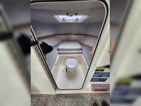 Interior view of a boat's bathroom area, featuring a toilet and a small sleeping space, showcasing the compact design of marine cabins.