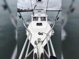 A view from the front of a fishing boat underway, showcasing the helm and fishing gear — perfect for anglers seeking adventure on the water.