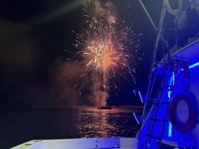 A stunning display of fireworks lights up the night sky as seen from a boat, creating a festive atmosphere perfect for celebrations on the water.