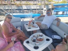 A group of friends enjoys drinks and snacks aboard a pontoon boat, perfect for a relaxing day on the water.