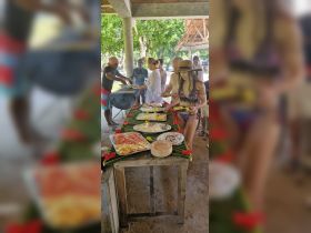 Guests enjoy a delicious BBQ spread featuring fresh fruits and grilled dishes, perfect for a tropical feast during a boat trip.