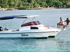 Two friends relax on the bow of a boat named 'Zico,' enjoying the serene waters — a perfect moment for leisure and camaraderie on the water.