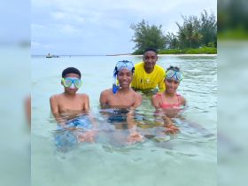 A group of children enjoying a fun snorkeling experience in shallow waters, interacting with starfish — a memorable wildlife encounter in a tropical paradise.