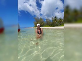 A woman enjoys a close encounter with a starfish while wading in crystal-clear waters, showcasing the beauty of marine life in a tropical paradise.
