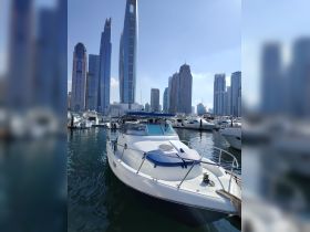 A sleek speedboat docked in a marina with a stunning cityscape backdrop, showcasing modern skyscrapers and a clear blue sky.