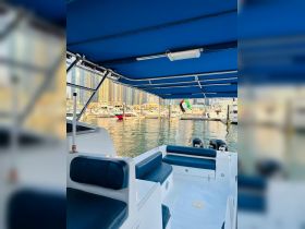 Interior view of a boat's seating area, showcasing comfortable seating and a well-equipped helm, perfect for a day on the water.