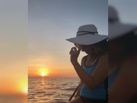 A woman enjoys a serene sunset on the water, capturing a moment of relaxation and beauty during a boating experience.