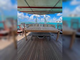 A beautifully arranged dining area on a boat, featuring a wooden table and comfortable seating, perfect for enjoying meals while cruising on the water.