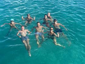 A lively group enjoys a refreshing swim in crystal-clear waters, capturing the essence of fun and relaxation on a perfect day out on the water.