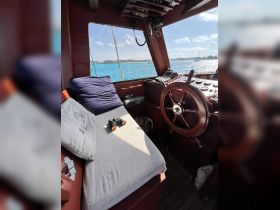 A cozy view of the helm area inside a boat, featuring comfortable seating and navigational equipment, perfect for a relaxing day on the water.