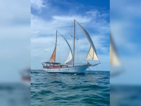 A stunning sailboat gracefully navigates the open waters under a clear blue sky, showcasing its elegant sails and classic design.