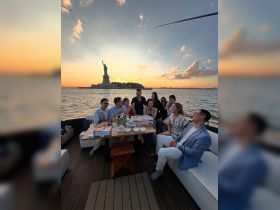 A lively group enjoys a sunset dinner cruise near the Statue of Liberty, celebrating with food and drinks — a perfect backdrop for memorable moments on the water.