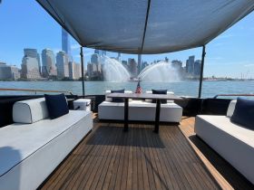 A stylish lounge area on a boat featuring comfortable seating and a stunning view of the city skyline, perfect for relaxing while cruising.