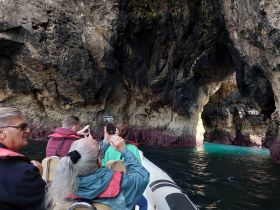 A group of adventurers captures the stunning rock formations while exploring a cave on a boat tour, showcasing the beauty of nature and the thrill of discovery.