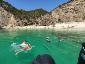 A family enjoys a refreshing swim in the crystal-clear waters near a beautiful beach, perfect for summer fun and relaxation.