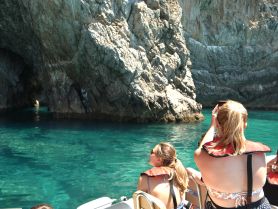 A group of friends enjoys a scenic boat tour, capturing the stunning rock formations and clear waters while exploring a cave — a perfect adventure for nature lovers.