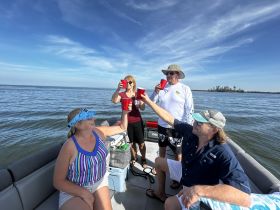 A lively group enjoys a toast on a boat, celebrating with drinks against a beautiful water backdrop — perfect for memorable outings and gatherings.