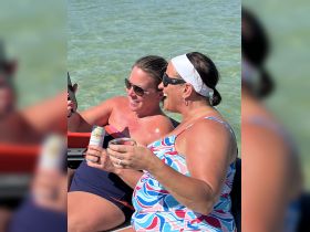 Two friends enjoy a fun day on the water, sharing drinks and laughter while soaking up the sun — a perfect moment for a memorable beach outing.