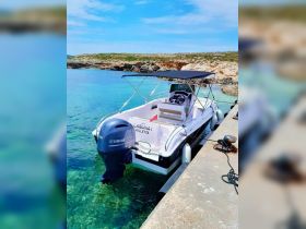 A sleek boat named 'Laguna I' docked in crystal-clear waters, showcasing its elegant design against a picturesque rocky backdrop.