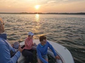 A group enjoys a serene sunset on the water, creating a perfect backdrop for memorable moments aboard the boat.