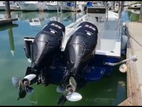 A detailed view of the back of a boat with twin outboard motors docked at the marina, showcasing its sleek design and readiness for adventure.