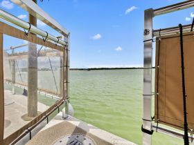 A view from inside a boat showcasing the cabin area with transparent panels and a serene water backdrop, perfect for enjoying the scenery while cruising.