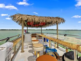 A spacious interior view of a boat's lounge area featuring a bar with seating, perfect for relaxing and enjoying drinks while on the water.