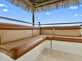 Cozy seating area inside a boat, featuring comfortable cushions and a shaded overhead, perfect for relaxing while enjoying the water.