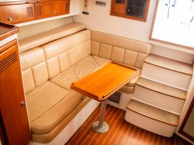 Cozy interior seating area of a boat featuring a comfortable lounge space and a wooden table, perfect for relaxing during trips on the water.