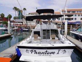 The back view of the 'Phantom I' yacht docked in Cabo San Lucas, showcasing its sleek design and inviting seating area, perfect for fishing or leisure trips.