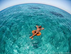A man relaxes on an inflatable float in the crystal-clear ocean, enjoying a serene moment in paradise — perfect for sun-soaked adventures.