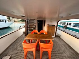 Interior view of a boat's dining area featuring orange chairs and a wooden table, perfect for enjoying meals while on the water.