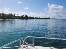 A serene view from the deck of a boat, showcasing calm waters and a lush coastline, perfect for a relaxing day on the water.