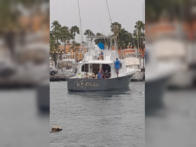 A lively group aboard the 'Ke pasa' boat at the marina, showcasing a fun fishing experience with friends and family.