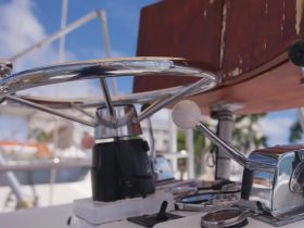 Close-up view of the helm and control console on a boat, showcasing the intricate details of steering and navigation equipment.