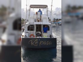 A fishing boat named 'Ke pasa' is docked at the marina with crew members preparing for a day on the water, showcasing the excitement of fishing adventures.