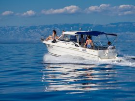 A group enjoys a sunny day cruising on a boat, showcasing the joy of on-water adventures against a stunning backdrop.