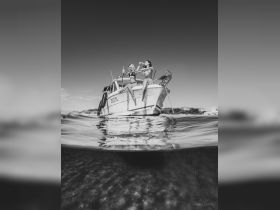 Two friends enjoy drinks and celebrate on the bow of a boat, capturing the essence of fun and relaxation on the water.