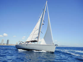 A sleek sailboat glides through the vibrant blue waters, showcasing a lively group enjoying their time on the water — perfect for sailing adventures.